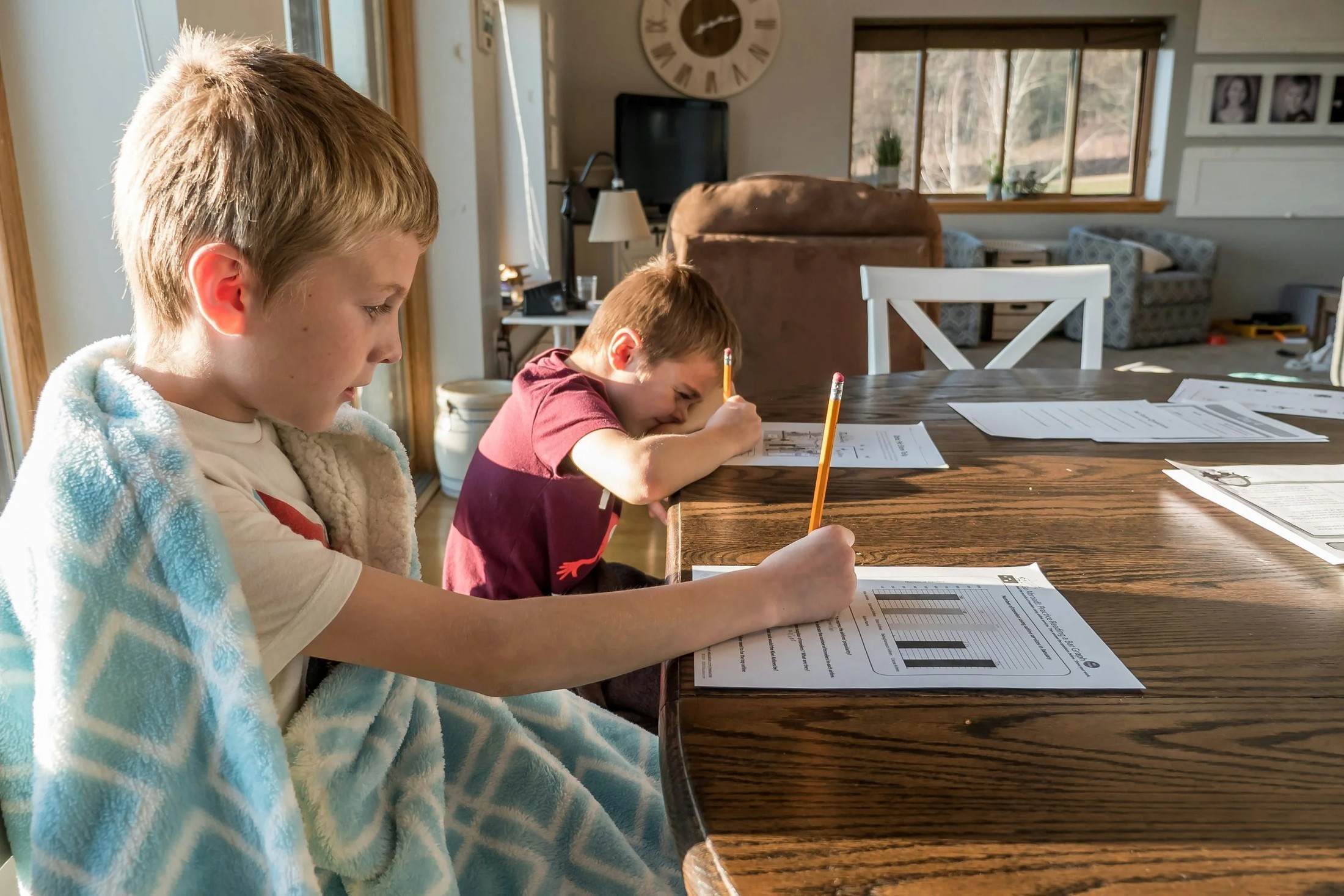 Two students doing schoolwork at a table at home